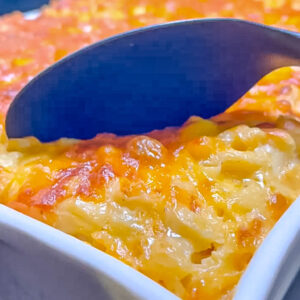 Pan of baked macaroni and cheese with a large black spoon