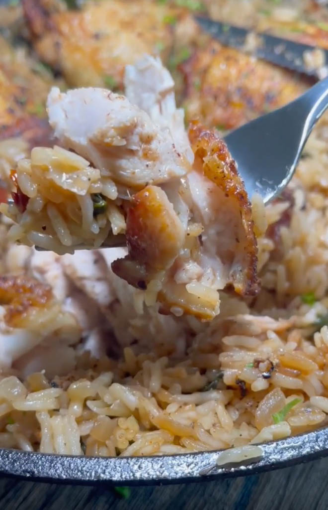 a forkful of chicken from a pot of one pan chicken and rice
