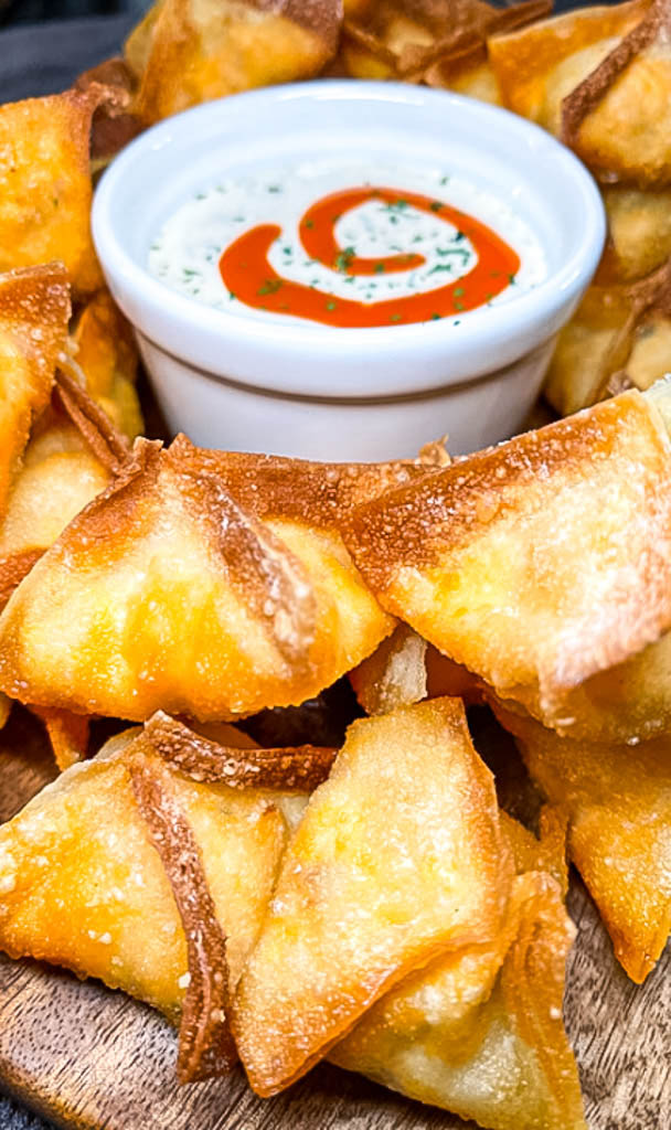 a platter of wontons with sauce in the center