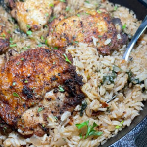 chicken thighs and rice in a skillet with a spoon