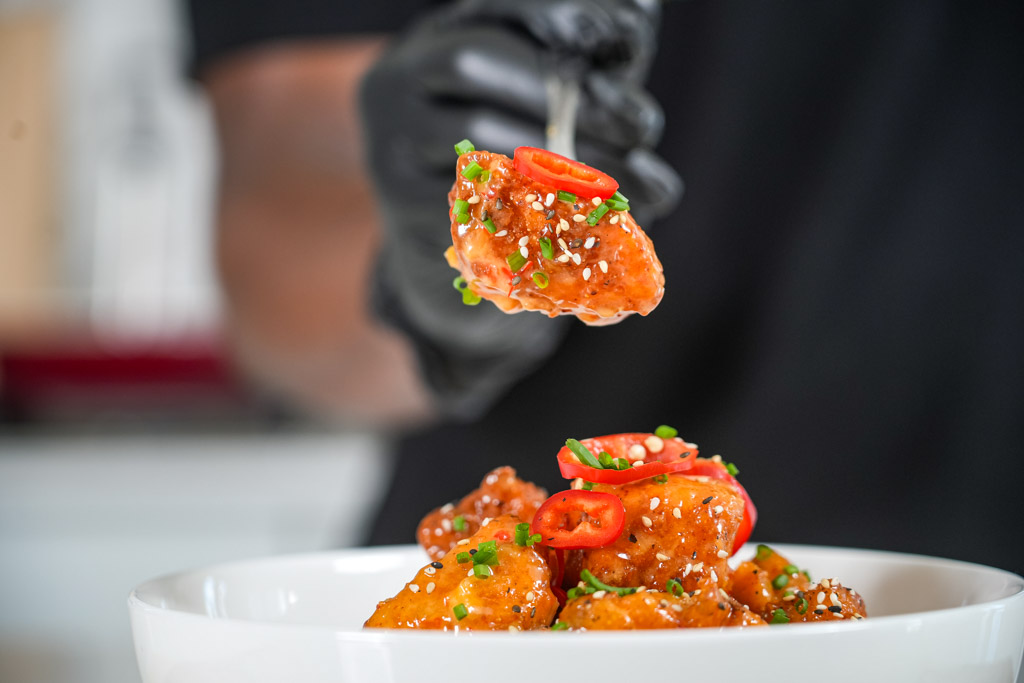 bang bang salmon bites held up in front of the camera on a fork