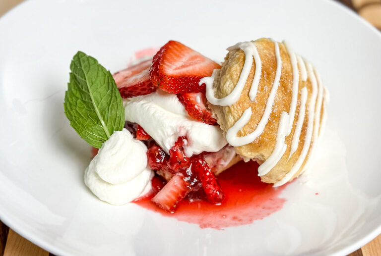 strawberry shortcake on a white plate with cream and biscuits