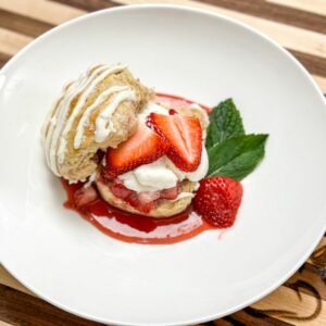 strawberry shortcake on a white plate with cream and biscuits