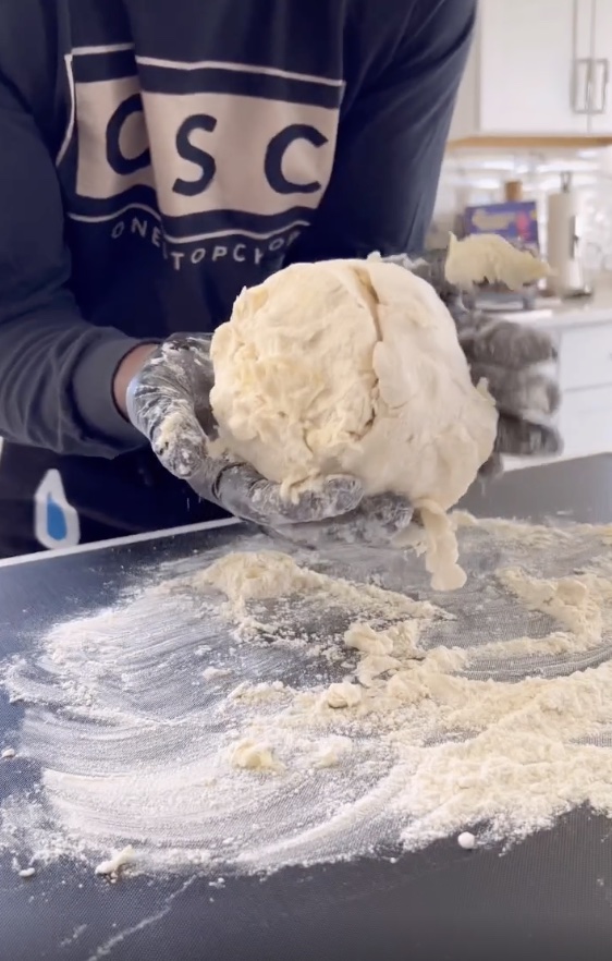 hands holding a large ball of dough to make biscuits