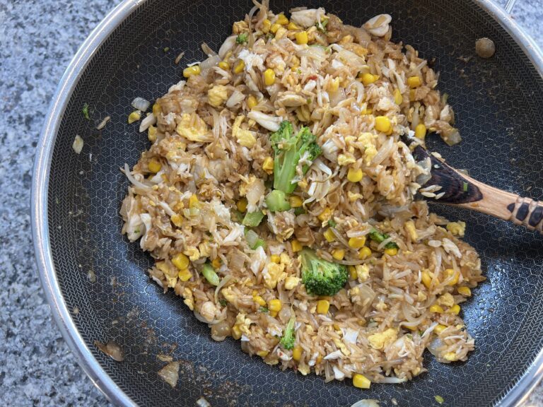 all ingredients for the crab fried rice have been added to a skillet and are being stirred.