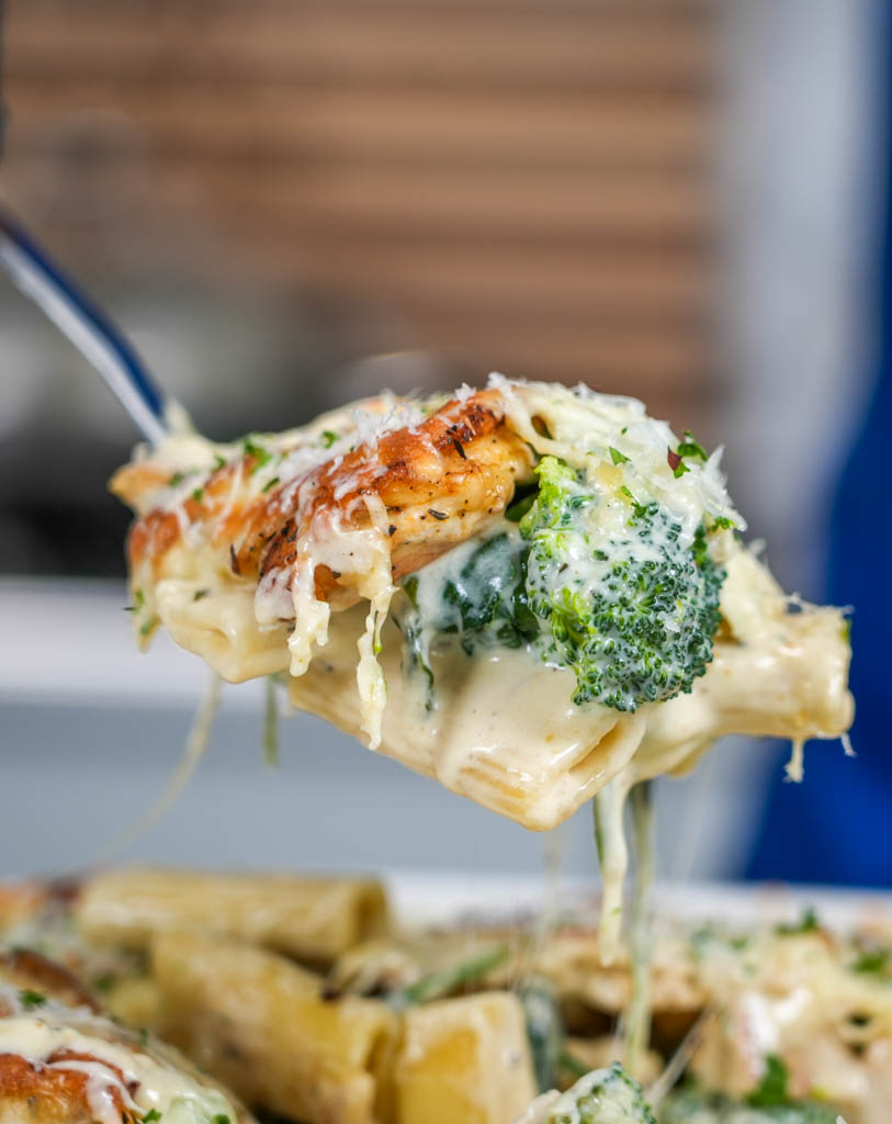 a close up of a spoonful of chicken and broccoli pasta bake