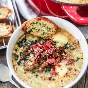 Zuppa Toscano Soup in a bowl served with crostini and topped with bacon.