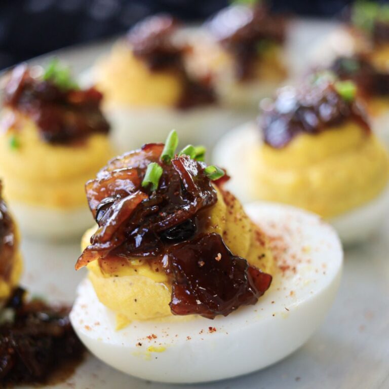 A close up picture of a deviled egg topped with bacon jam