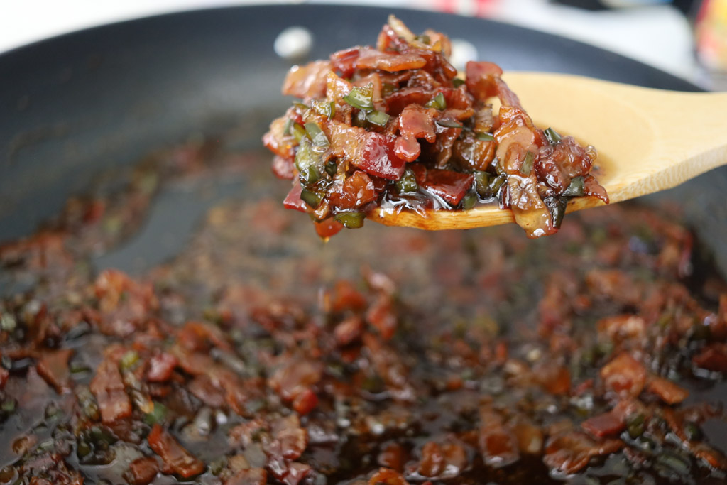 Bacon jam filling being spooned out of the frying pan.