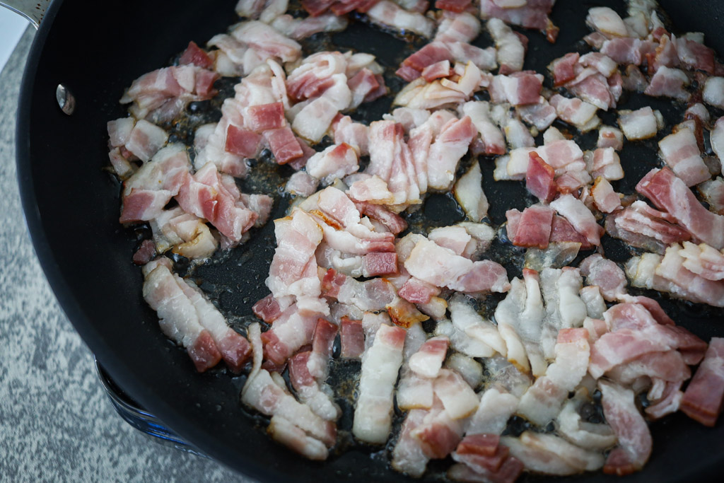 Uncooked, chopped bacon in a frying pan.