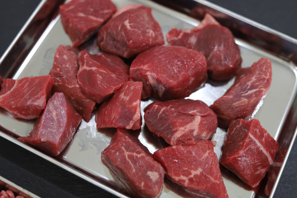 Uncooked cubed chuck roast on a baking sheet.