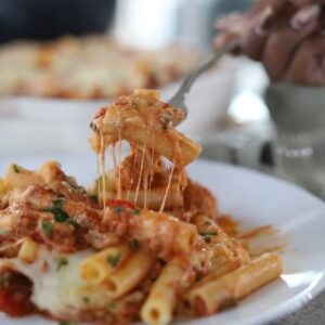 Baked Ziti on a plate being eaten with a fork.