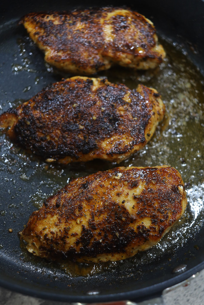 chicken breasts cooking in a pan with oil.