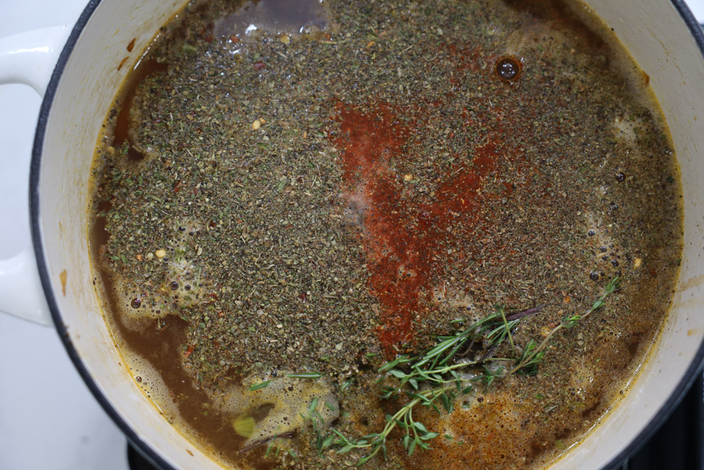 Seasonings, rosemary, and thyme being added into the chicken broth.