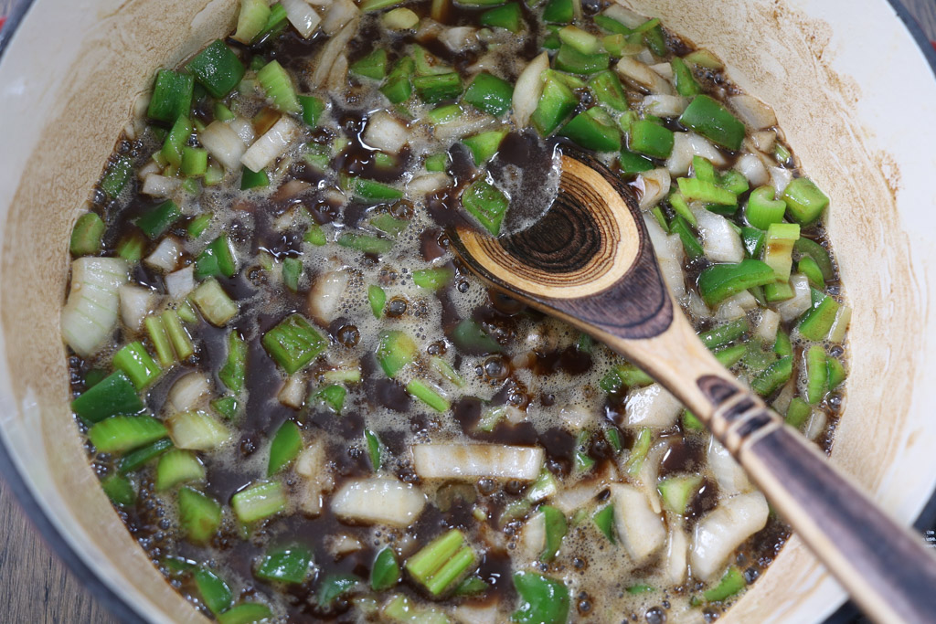 Green peppers, onions, and stock in a dutch oven.
